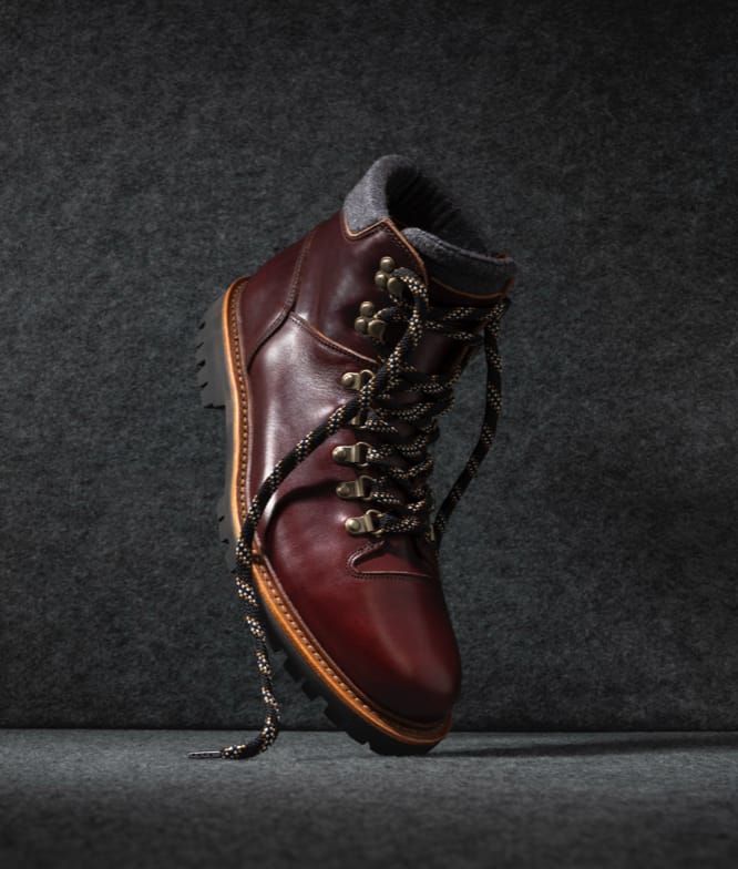 One burgundy leather hiker boot displayed vertically with the toe facing downward and laces untied.  