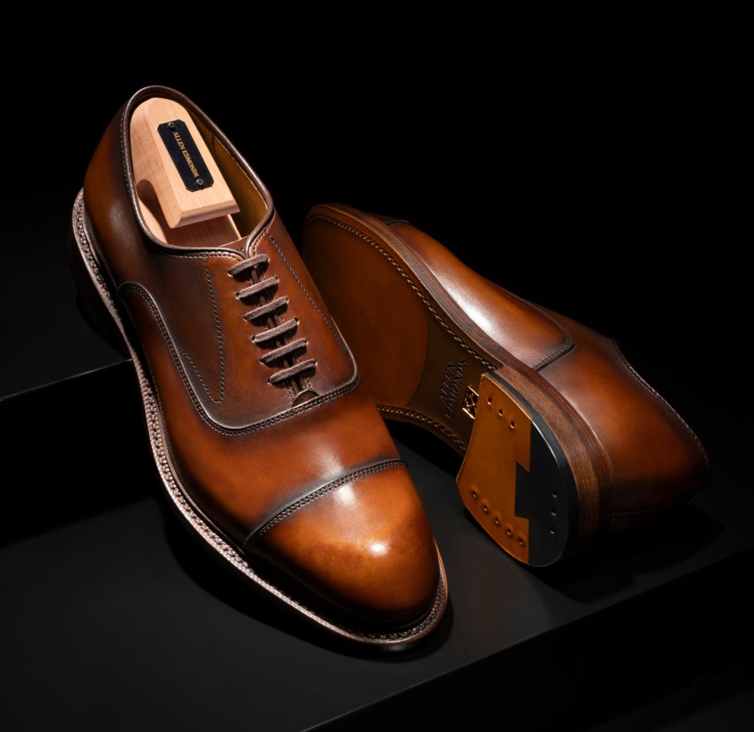 Allen Edmonds Manhattan Reserve coffee leather oxfords with a wooden shoe tree and visible leather sole.